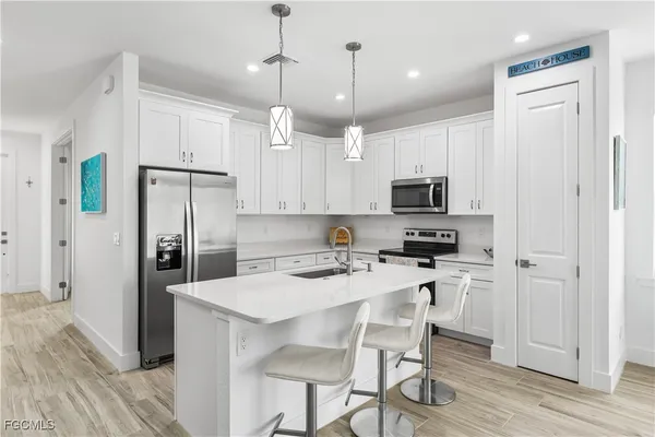 a kitchen with stainless steel appliances granite countertop a refrigerator a stove microwave and white cabinets with wooden floor