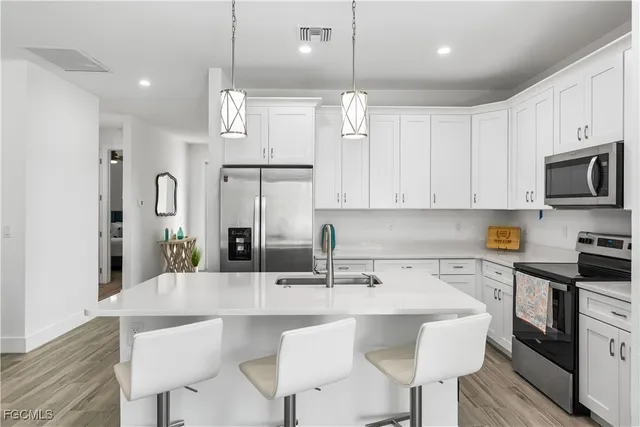 a kitchen with stainless steel appliances a sink a stove a refrigerator and cabinets