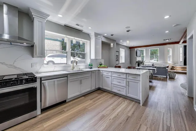 a kitchen with a sink wooden floor stainless steel appliances and windows