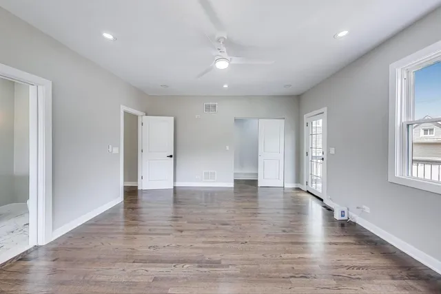 a view of an empty room with wooden floor and windows