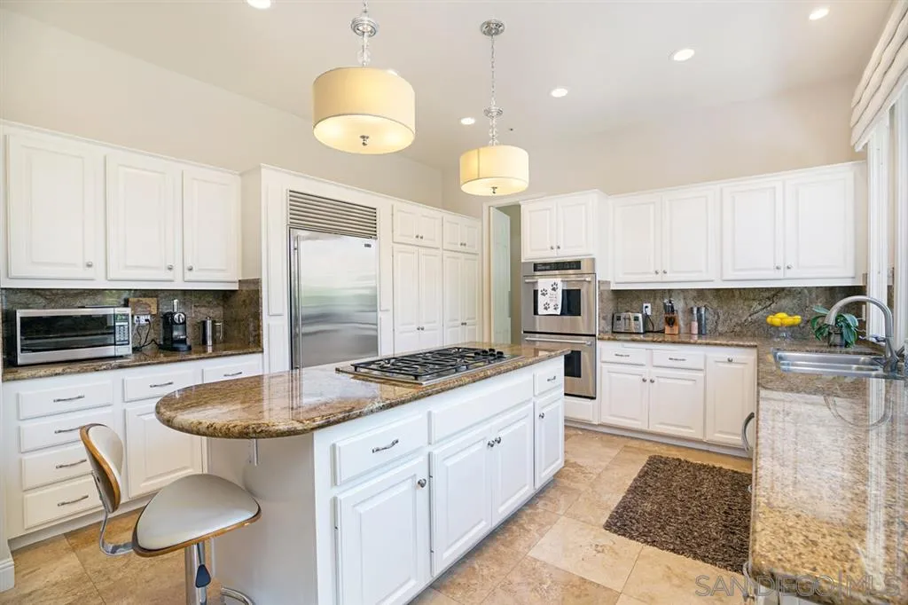 14150 Steeple Chase Row San Diego, CA 92130 - Photo 10 of 25 a kitchen with stainless steel appliances granite countertop a sink a stove cabinets and chairs