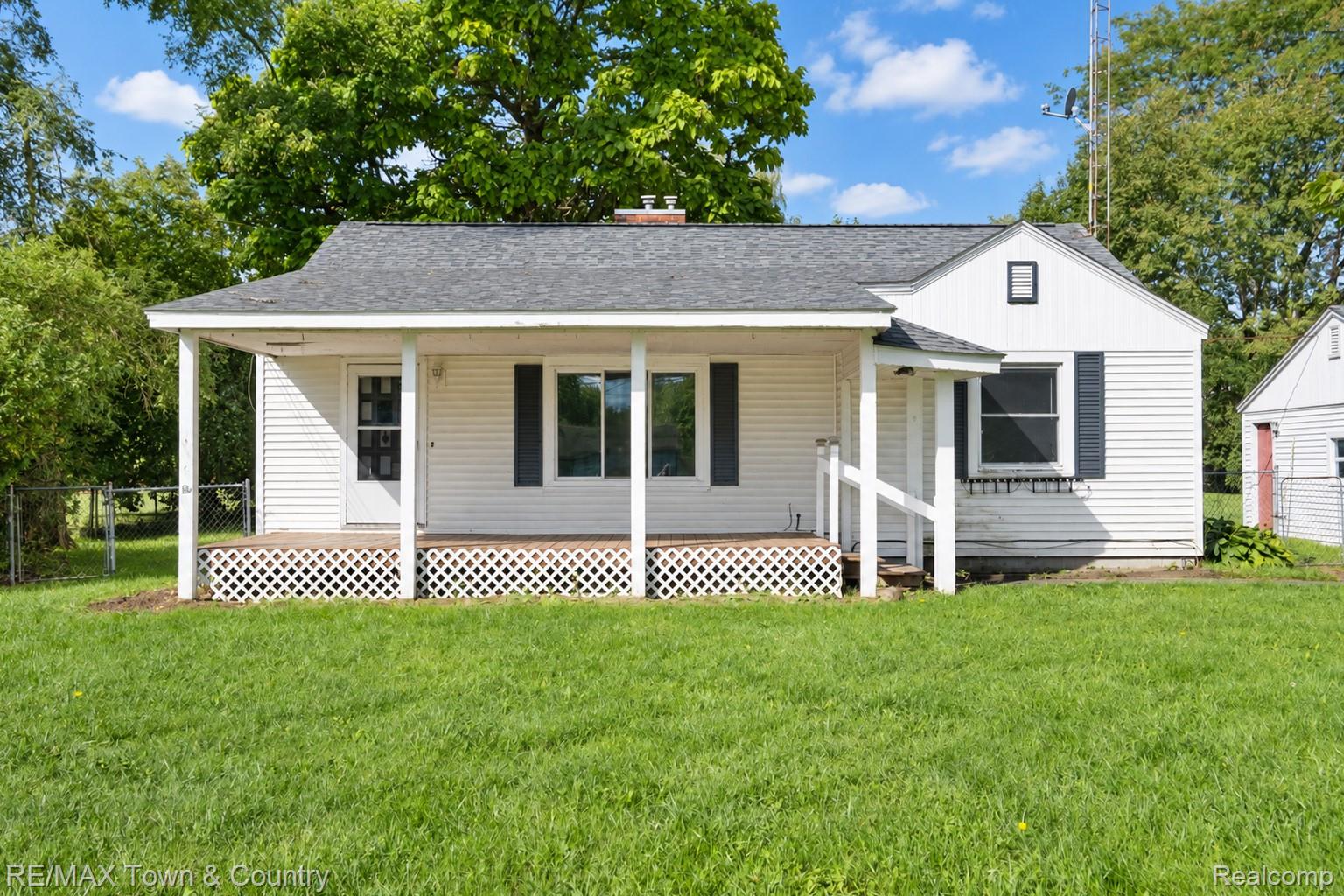 300 Elms Road Flushing, MI 48433 - Photo 5 of 26 White siding exterior with a dark shingle roof and a covered porch