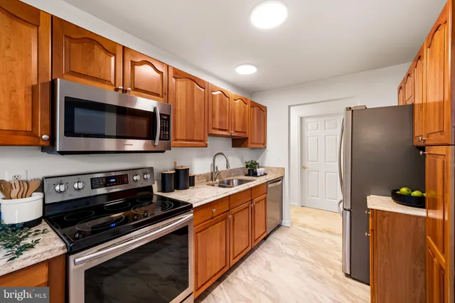 a kitchen with stainless steel appliances a stove a sink a microwave a refrigerator and cabinets