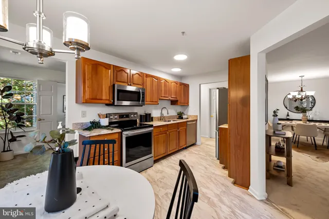 a kitchen with stainless steel appliances kitchen island granite countertop a refrigerator a stove top oven a sink dishwasher and dining table with wooden floor