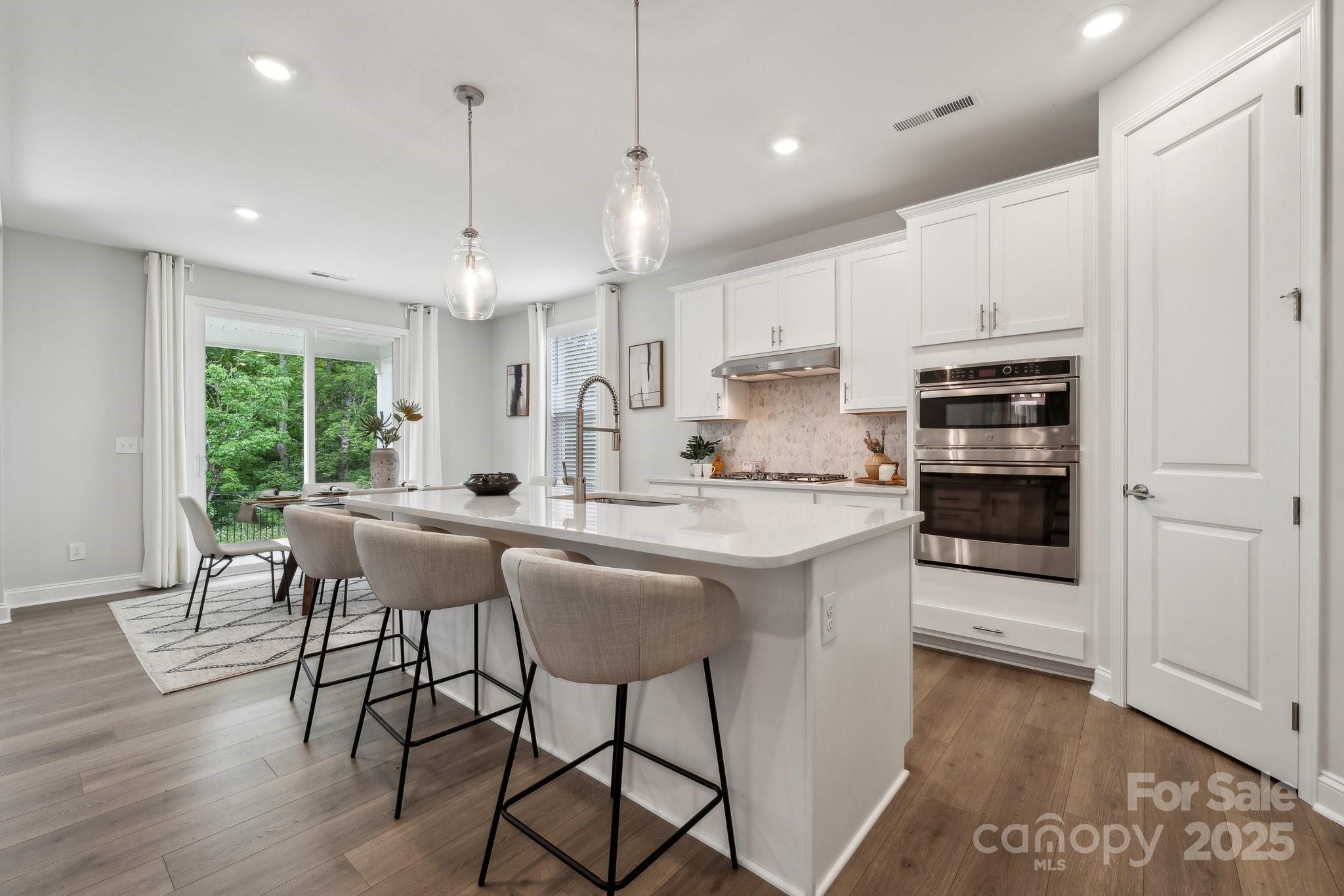 a kitchen with kitchen island a dining table chairs and wooden floor