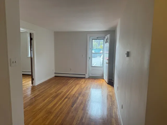 a view of a room with wooden floor and a refrigerator