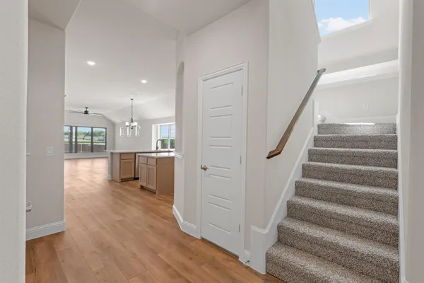 a view of a hallway with wooden floor and a kitchen
