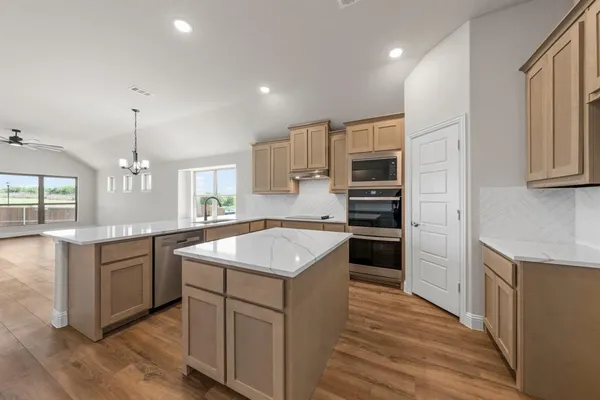 a kitchen with kitchen island granite countertop a sink cabinets and stainless steel appliances