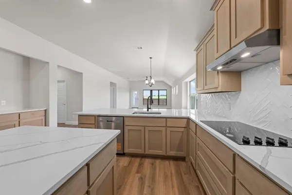 a kitchen with a sink dishwasher a stove and white cabinets with wooden floor