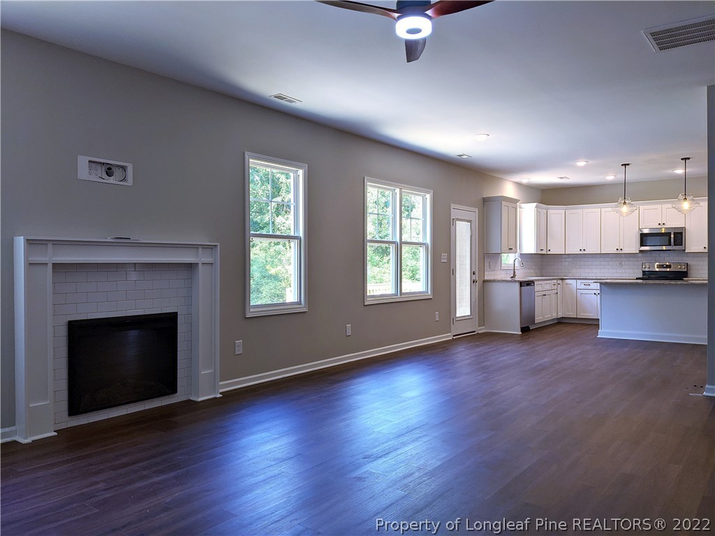 2903 Rockfish Road Raeford, NC 28376 - Photo 6 of 28 an empty room with wooden floor fireplace and windows