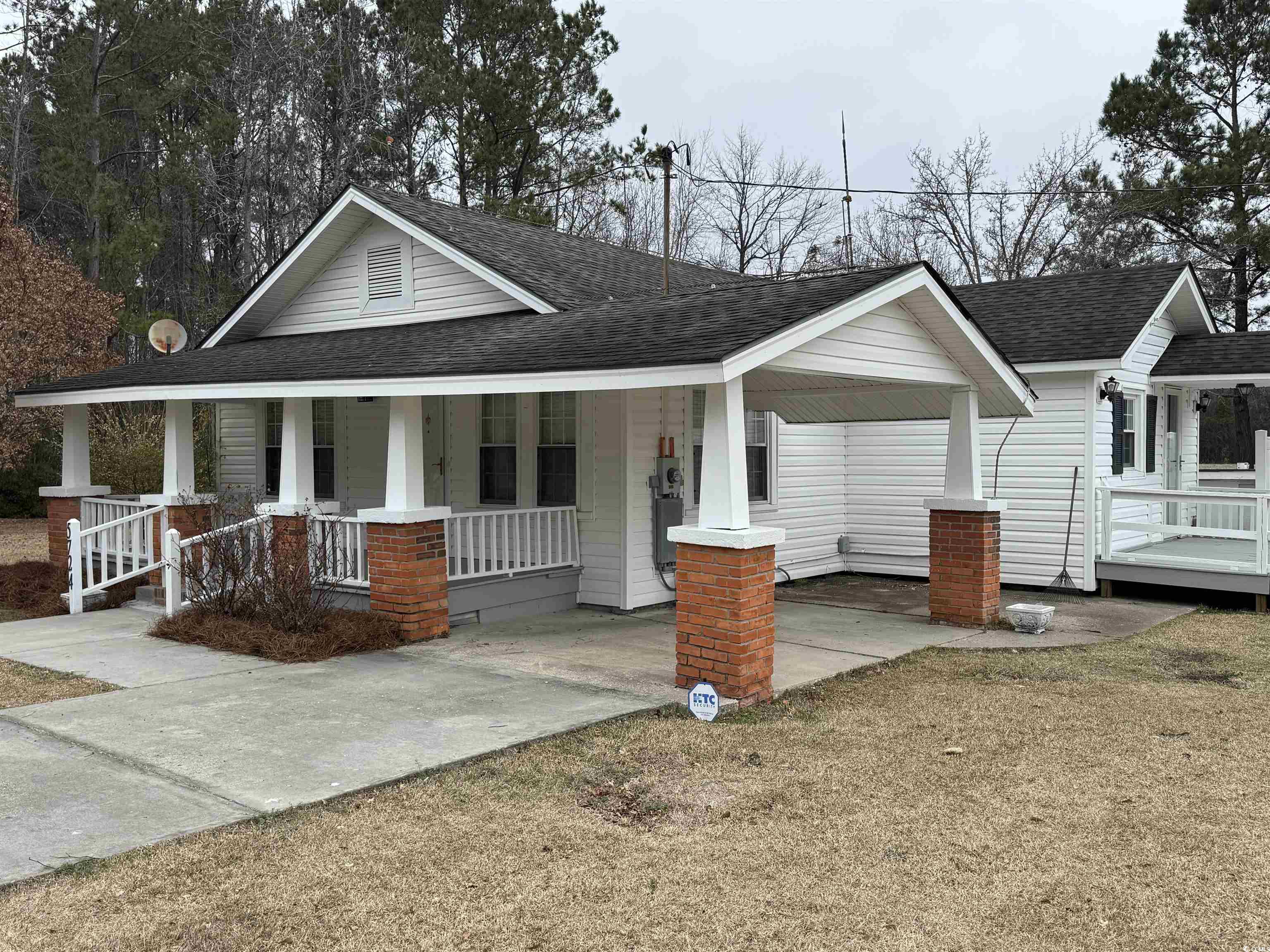 View of front facade with roof with shingles, covered porch, an attached carport, and driveway