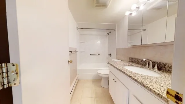 a bathroom with a granite countertop sink a toilet and shower