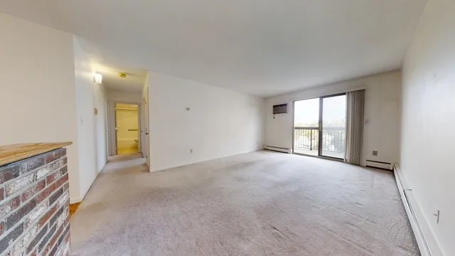 a view of an empty room with a window and a kitchen