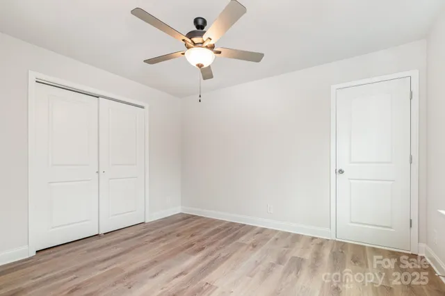 an empty room with wooden floor fan and windows