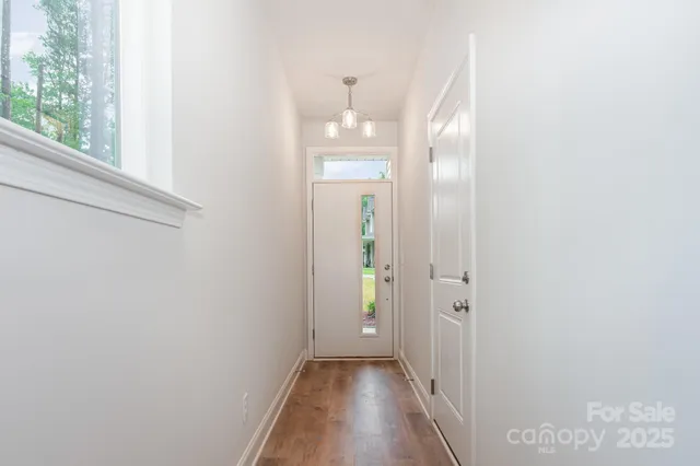 a view of a hallway with wooden floor and a bathroom