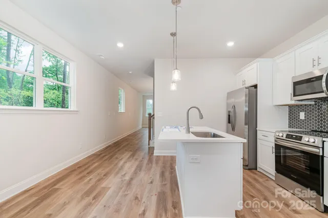 a kitchen with stainless steel appliances granite countertop a sink a stove and a refrigerator