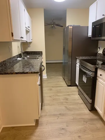 a kitchen with stainless steel appliances granite countertop a refrigerator a stove and a sink with wooden floor