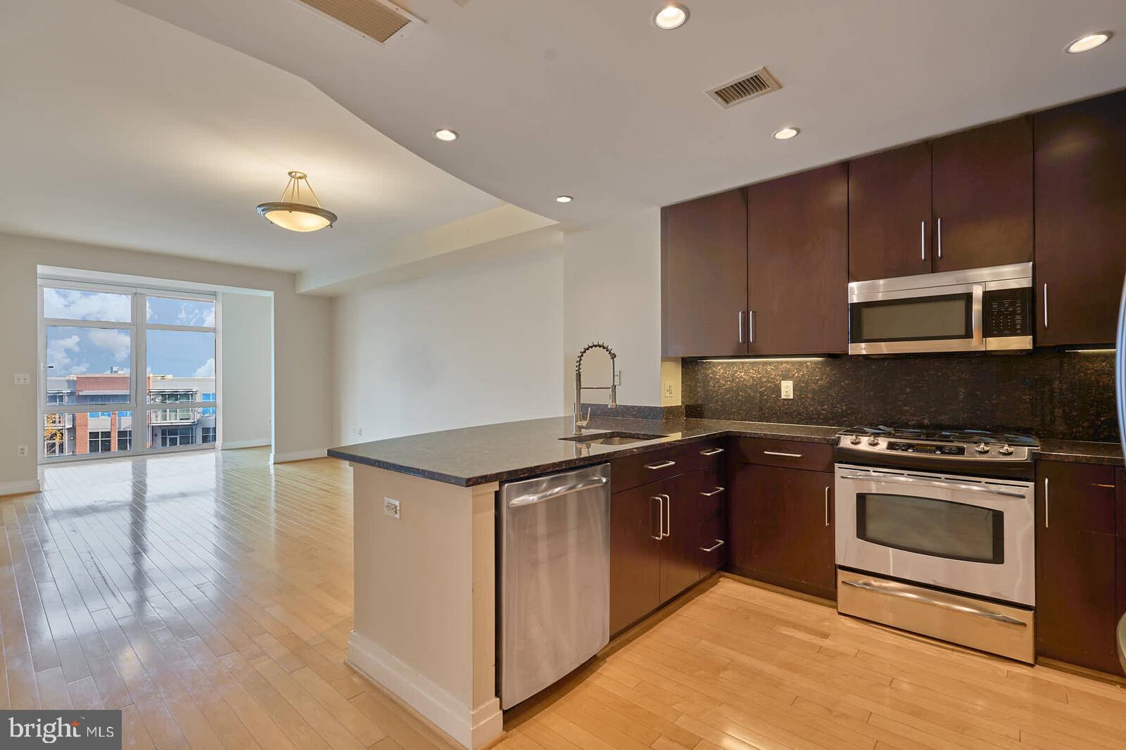 a kitchen with stainless steel appliances granite countertop a stove a sink and a microwave