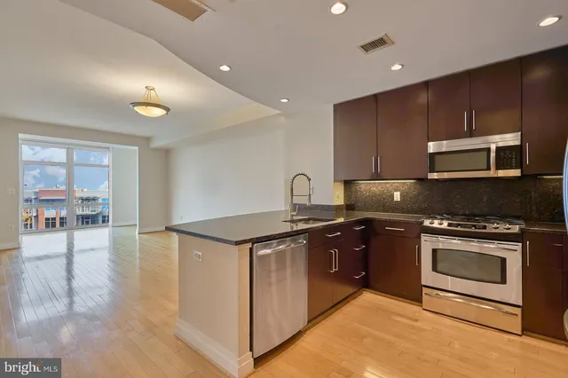 a kitchen with stainless steel appliances granite countertop a stove a sink and a microwave