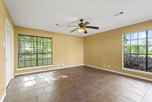 a view of empty room with window and chandelier fan