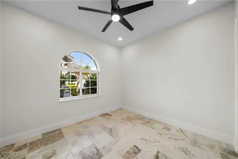 an empty room with a window and ceiling fan