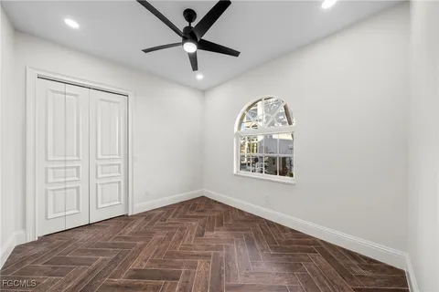 an empty room with wooden floor ceiling fan and windows