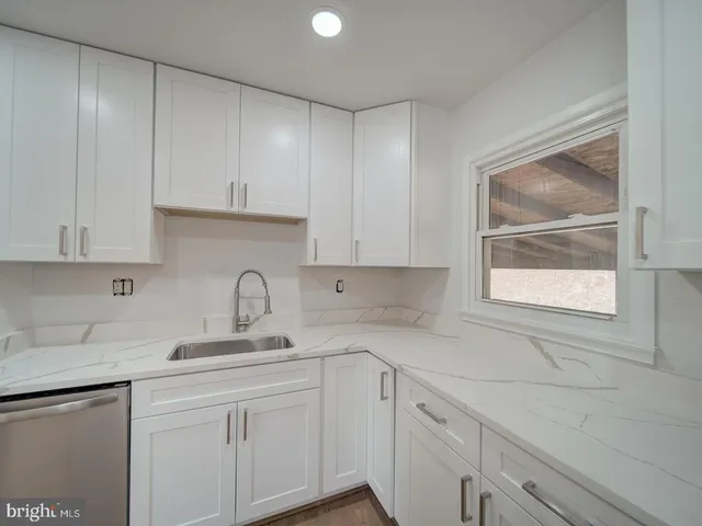 a kitchen with white cabinets and window