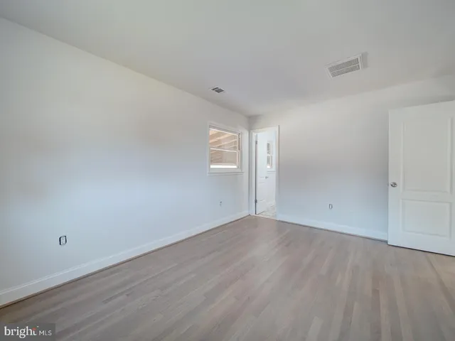 an empty room with wooden floor and window