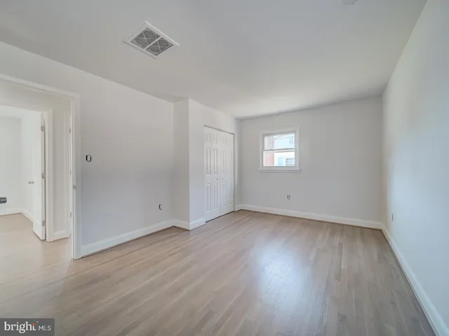 an empty room with wooden floor and window