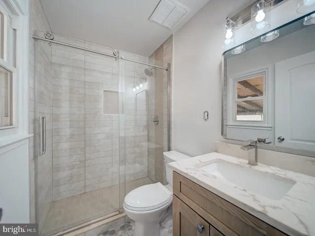 a bathroom with a granite countertop sink toilet and shower