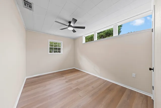 a view of empty room with wooden floor and fan