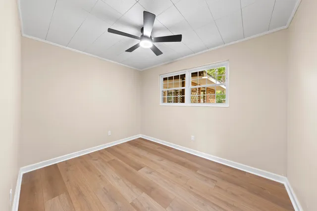 an empty room with windows and fan
