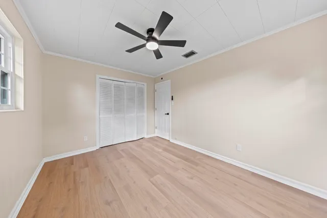 an empty room with wooden floor fan and windows