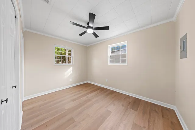 a view of empty room with wooden floor and fan