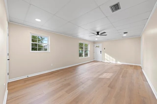 an empty room with wooden floor and windows