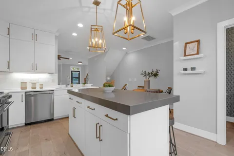 a kitchen with stainless steel appliances a refrigerator a stove a sink and chairs