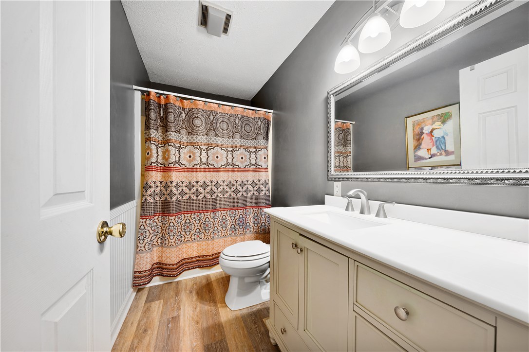 139 Tulip Lane Westminster, SC 29693 - Photo 12 of 37 Wood-look flooring grounds this well-appointed bathroom, featuring a vanity with a large mirror and a shower-tub combination.