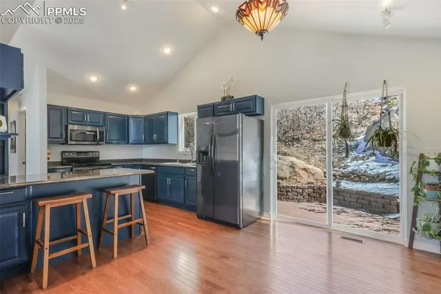 a kitchen with stainless steel appliances granite countertop a sink dishwasher stove and refrigerator with wooden floor