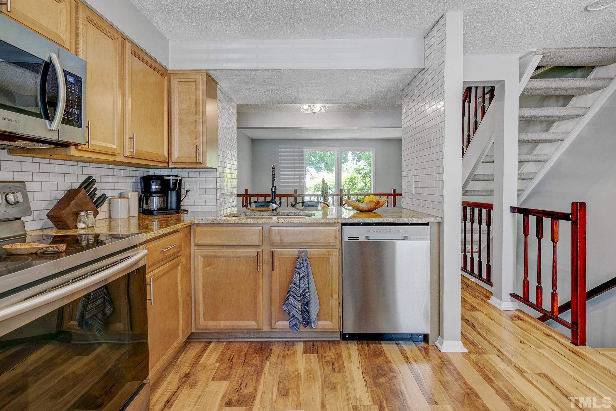 7706 Ohmann Court Raleigh, NC 27615 - Photo 8 of 27 a kitchen with stainless steel appliances wooden floor and a refrigerator