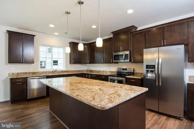 a kitchen with stainless steel appliances granite countertop a sink a stove and a refrigerator