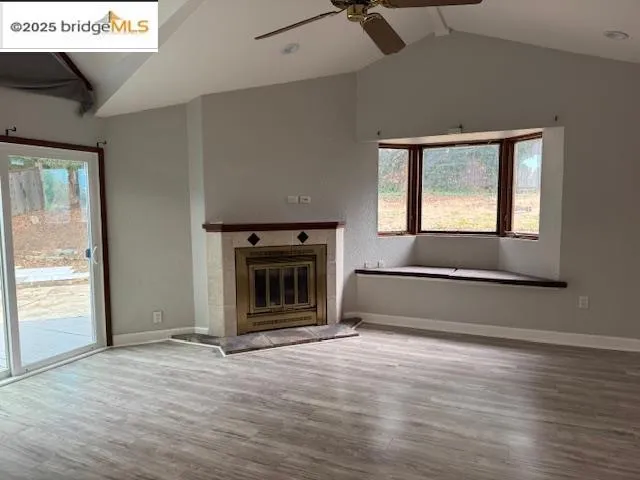 an empty room with windows fireplace and wooden floor