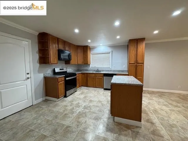 a large kitchen with stainless steel appliances granite countertop a stove a sink a refrigerator and a microwave