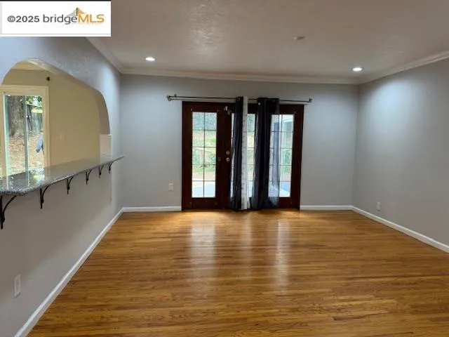 a view of an empty room with window and wooden floor