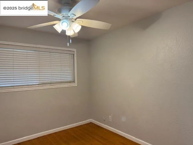 a view of a small space with wooden floor and a chandelier fan