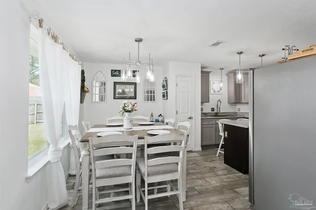 a kitchen with granite countertop a refrigerator a stove a sink dishwasher a dining table and chairs