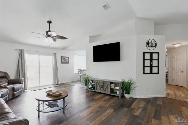 a living room with couches a fireplace and a dining table with wooden floor