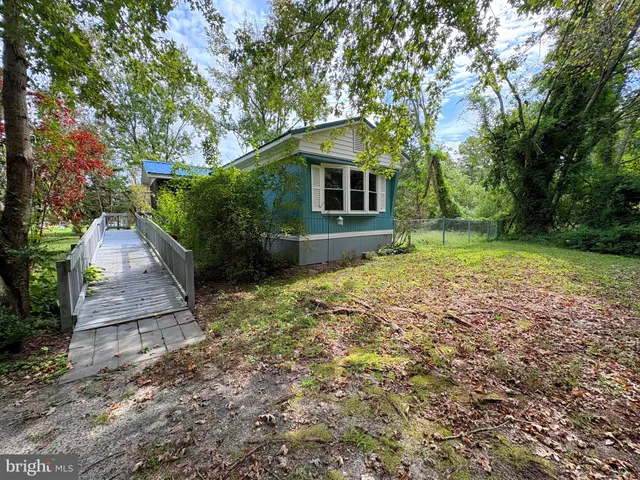 a backyard of a house with large trees and wooden fence