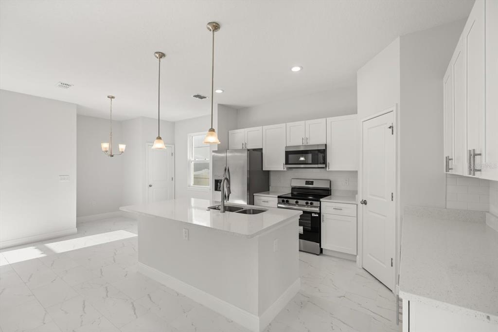 1289 Ash Tree Cove Casselberry, FL 32707 - Photo 6 of 34 a kitchen with stainless steel appliances kitchen island granite countertop a refrigerator a stove top oven a sink and kitchen island