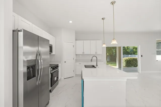 a kitchen with stainless steel appliances a refrigerator a sink a stove and a window