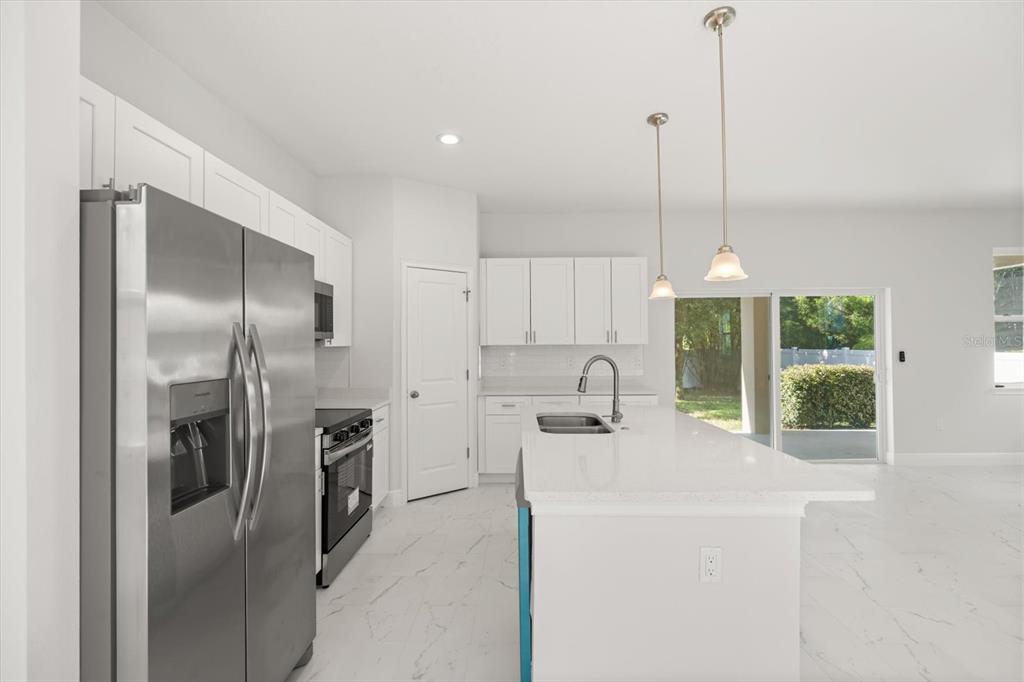 1289 Ash Tree Cove Casselberry, FL 32707 - Photo 7 of 34 a kitchen with stainless steel appliances a refrigerator a sink a stove and a window